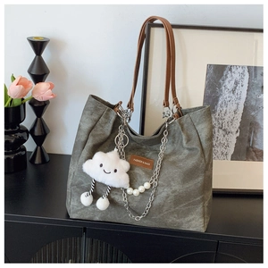 Detail of dark grey canvas tote with brown leather straps and cloud charm accessory
