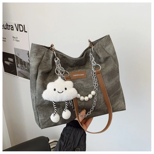 Detail of grey washed denim tote bag featuring metal chains and plush cloud pendant