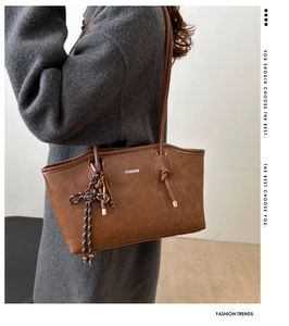 Brown vintage faux leather tote bag showing woven knot detail and long shoulder strap