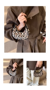 Detail of trendy crescent leopard print handbag with golden zipper and black leather handle