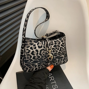 Chic leopard print shoulder bag with gold clasp and chain strap on a modern white chair