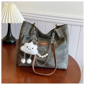 Detail of grey canvas tote with brown handle, metal chain strap and cloud plush charm