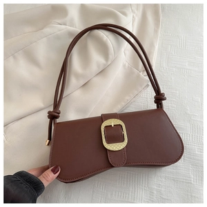 Détail d'un sac en cuir marron rétro avec grande boucle dorée tressée et bandoulière à nœuds
