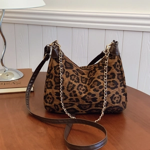 Vintage leopard print shoulder bag with gold chain and dual straps on wooden desk