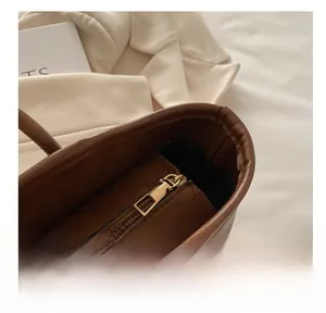Close-up of smooth golden metal zipper and brown leather texture on tote bag
