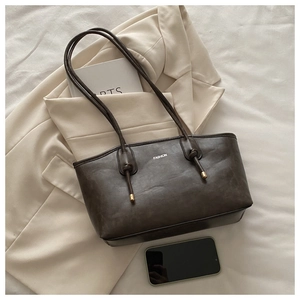 Detail of vintage brown tote bag showing fashion print and knotted strap with gold metal