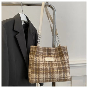 Detailed view of the plaid pattern fabric and leather brand tag on the tote bag