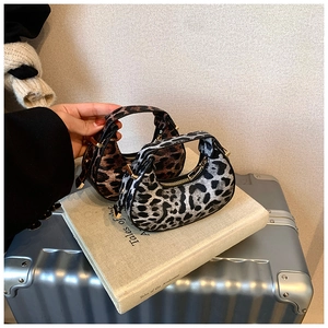 Detail view of leopard print crescent hobo bags with gold zippers on a suitcase