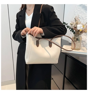 Detail of minimalist cream tote bag with brown leather straps and fine stitching texture