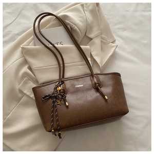 Detail of a brown leather tote bag with FASHION print and a metal key pendant
