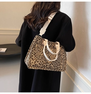 Leopard print canvas tote bag detail showing dual handles and a long shoulder strap