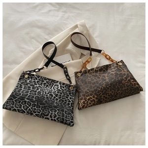 Close-up of leopard print tote bags with resin chain straps on a white blazer