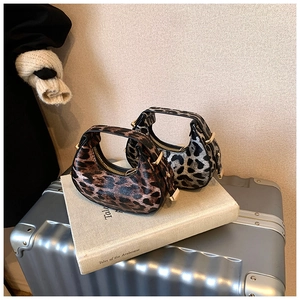 Detail of leopard print crescent moon bags with golden zipper on travel suitcase