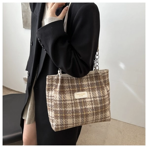Detail of checkered tote bag featuring leather logo tag and metal chain shoulder strap