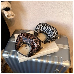 Detail of trendy crescent armpit bags in brown and grey leopard print with gold zippers