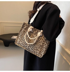 Detail of leopard print tote bag with white adjustable shoulder strap on black coat