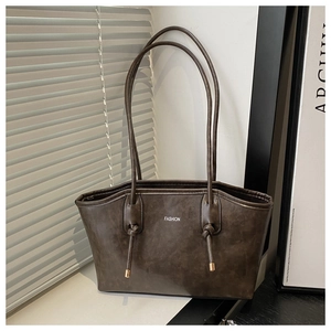 Detail of dark brown vintage tote bag showing knotted straps and fashion logo accents