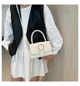 White crossbody bag featuring a distinctive gold U-buckle and textured leather finish