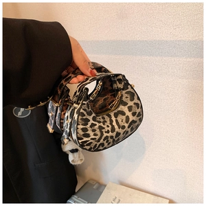 Detail of leopard print crescent bag with golden metal hardware and curved handle