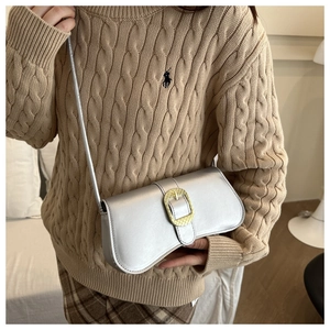 Detail of silver rectangle shoulder bag featuring a large golden textured buckle