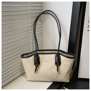 Detail of cream tote bag featuring black contrast trim and gold metal strap accents