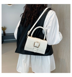 Chic white leather crossbody bag with gold buckle shown on a model in a trendy outfit