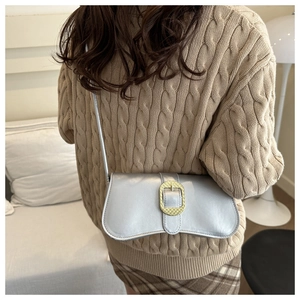 Detail of silver shoulder bag with large gold buckle styled with beige knit sweater
