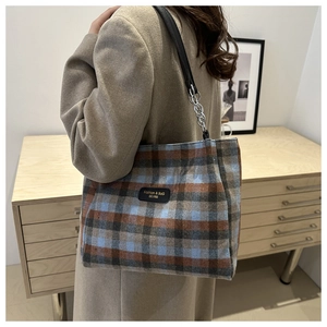 Détail du sac cabas à carreaux avec bandoulière en cuir et chaîne en métal sur l'épaule