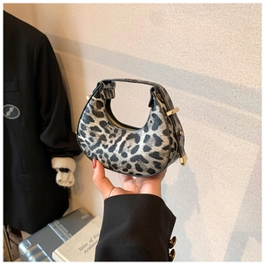 Close-up of a leopard print crescent handbag with gold hardware and zipper detail