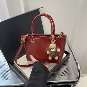 Modische dunkelrote Eimertasche mit Plüschanhänger und langem Schultergurt Damen
