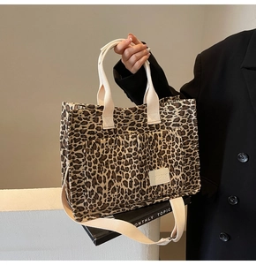Detail of leopard print tote bag featuring two front pockets and woven dual handles