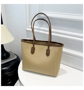 Detail of minimalist tote bag with contrast brown trim on textured beige faux leather
