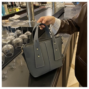 Detail of lychee pattern grey tote bag with contrast stitching and gold metal hardware