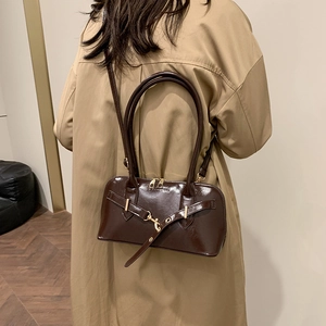 Retro deep brown glossy leather tote bag with gold buckle shown on minimalist model outfit