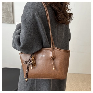 Detail shot of brown vintage faux leather tote bag with white fashion logo and shoulder strap