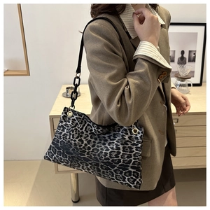 Detail of trendy leopard print shoulder bag featuring black acrylic chain and gold hardware