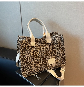 Macro detail of leopard print canvas tote featuring leather brand label and strap texture
