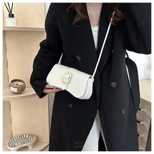 Close-up of white leather shoulder bag featuring a vintage golden textured metal buckle