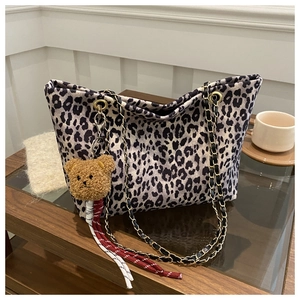 Dettaglio ravvicinato della borsa tote leopardata con catena dorata e ciondolo a orso
