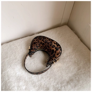 Detail view of leopard print crescent bag featuring golden zipper and plush texture