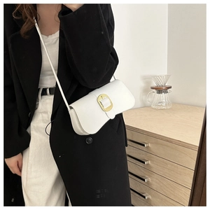 Detail of white half-moon crossbody bag with textured gold oval buckle on matte leather