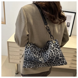 Detail van luipaardprint schoudertas met zwarte ketting gedragen op een kaki blazer
