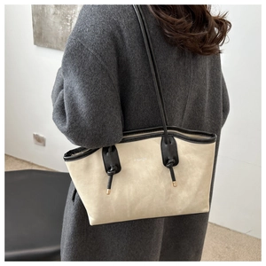 Detail of beige and black contrast stitching tote bag with knot strap and Fashion logo