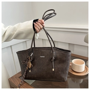 Close-up of a vintage dark brown tote bag featuring FASHION text and a tassel detail