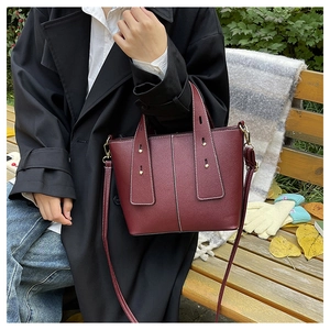 Close-up of deep burgundy pebbled leather tote with contrast white stitching and gold studs