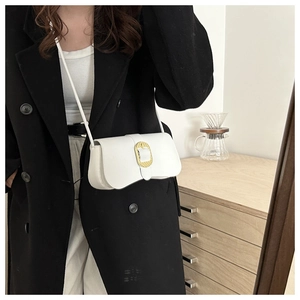 Gros plan d'un sac bandoulière en cuir blanc avec fermoir doré sur un manteau noir élégant