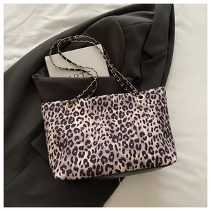 Dettaglio della borsa tote leopardata con catena dorata e tracolla in pelle intrecciata