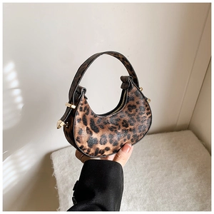 Close-up of leopard print crescent bag featuring gold zippers and metallic hardware