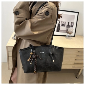 Detail of vintage black matte leather tote bag with FASHION text and key charm