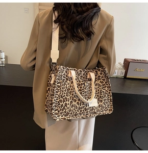 Detail of leopard print tote bag featuring a branded logo patch and wide shoulder strap